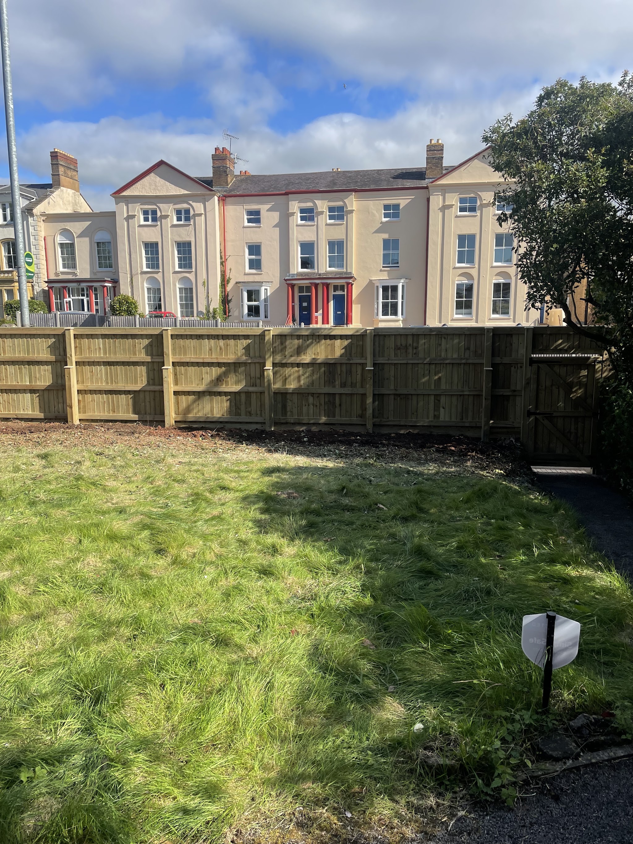 A new closeboard fence and matching gate around a lawn, with a Georgian terrace behind